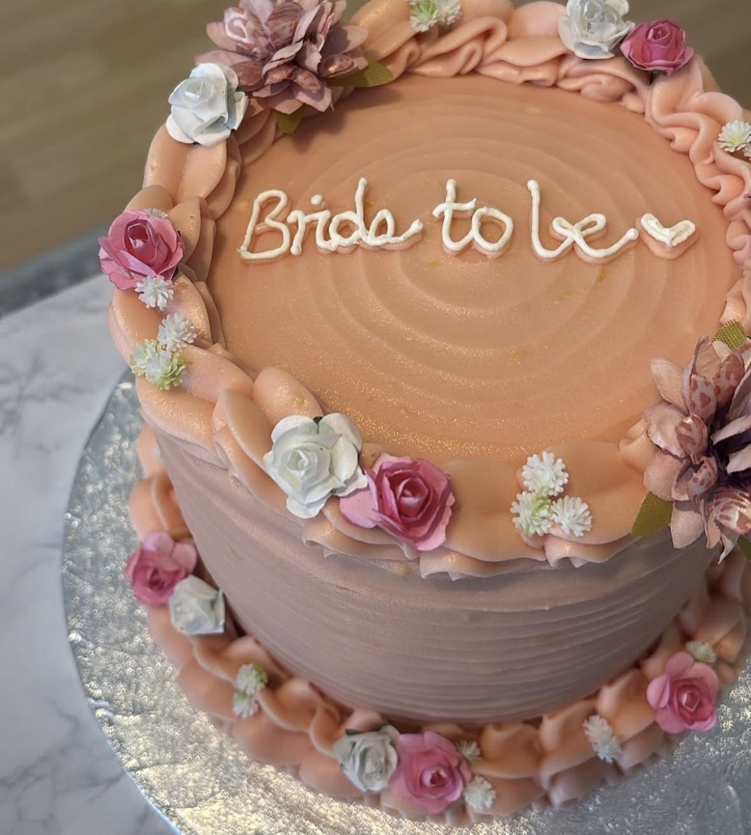 Peach-pink cake with “Bride to be” on top, ruffled borders and pink and white sugar roses (photo 2 of 3)