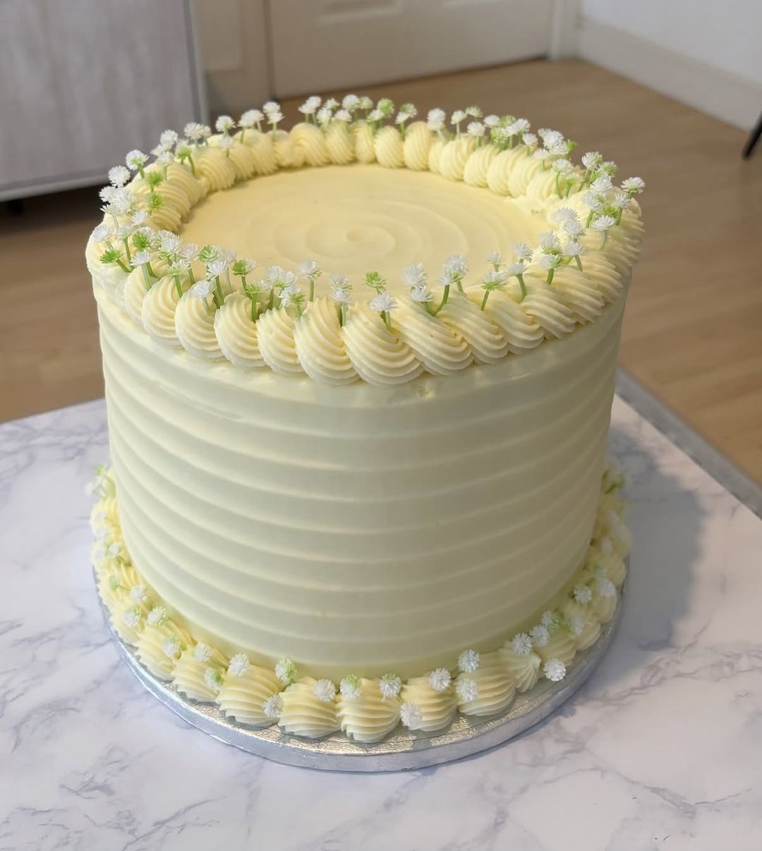 Tall ivory cake with combed sides, shell borders and tiny white flowers (photo 2 of 2)