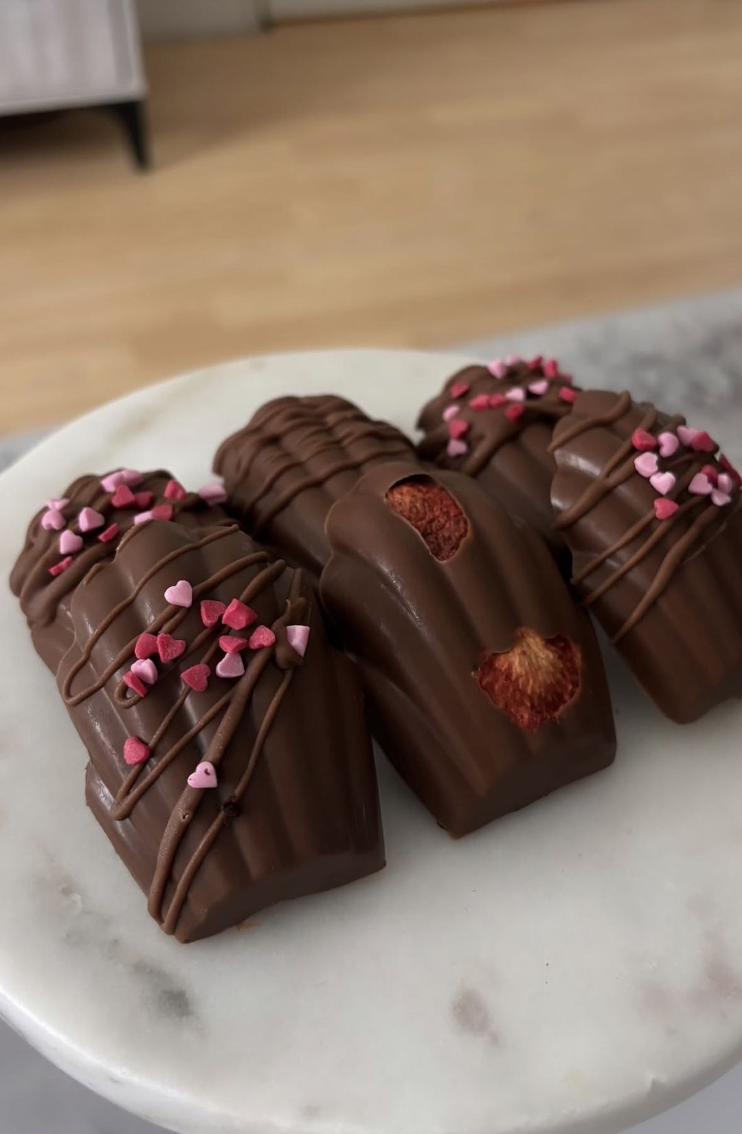 Chocolate-dipped madeleines decorated with pink sugar hearts