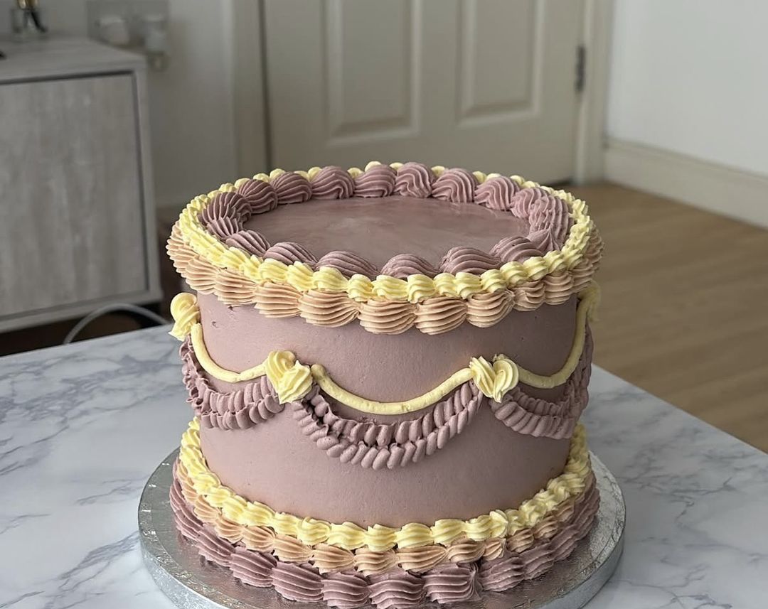 Mauve vintage cake with butter-yellow and lilac shell piping and swag garlands (photo 1 of 2)