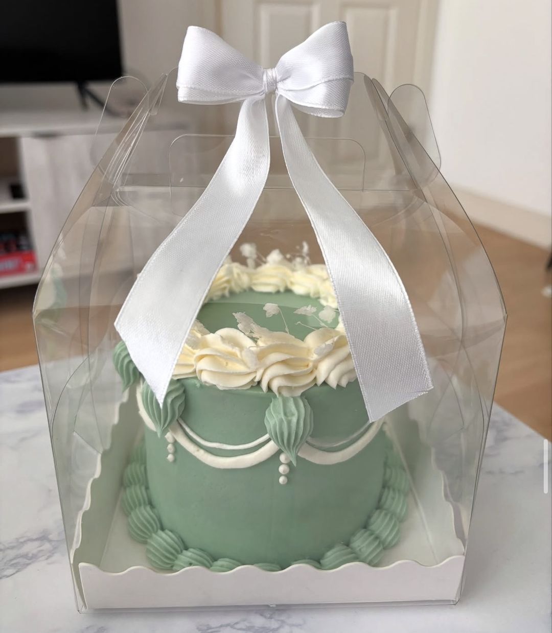 Sage green vintage bento with cream piping and pearl drops, tied with a white satin bow (photo 1 of 2)